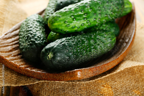 Fresh cucumbers in rustic bowl on  wooden background