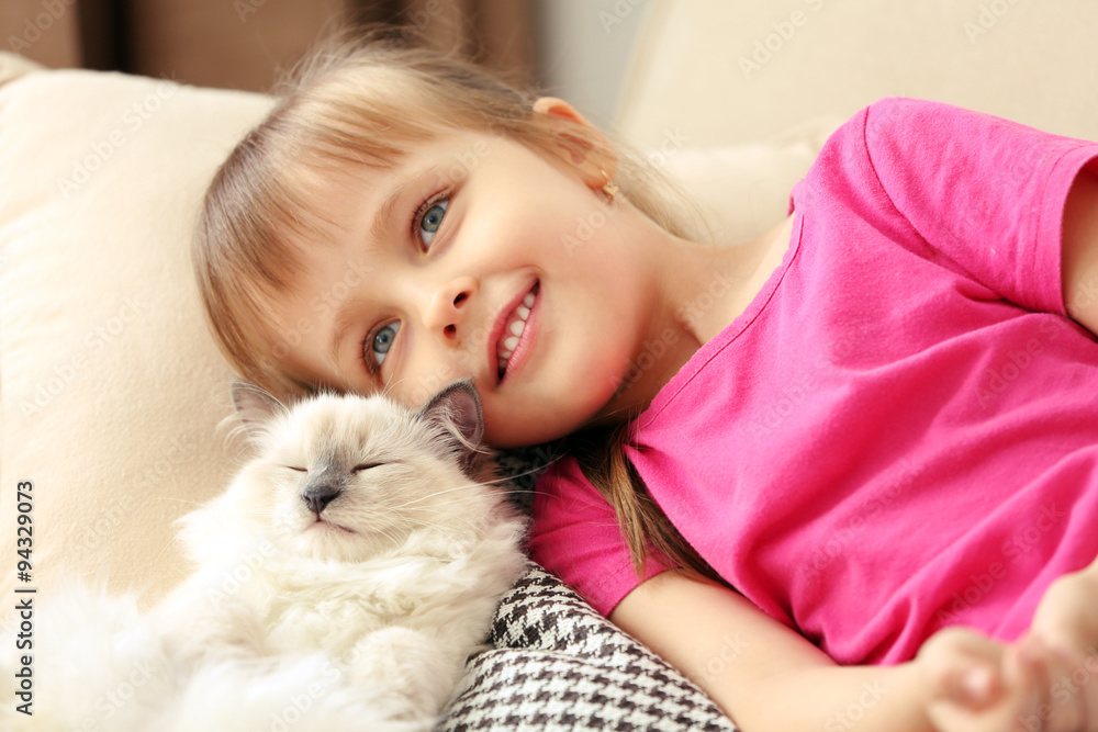 Little cute girl with kitten on sofa at home Little cute girl with kitten on sofa at home