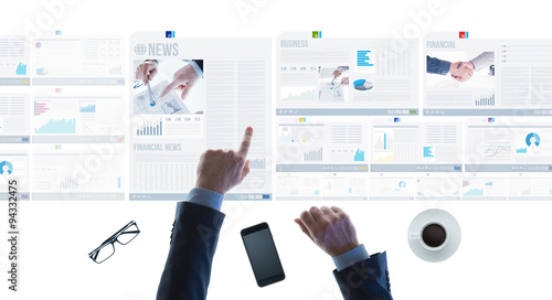 Businessman pointing at financial reports and news slides