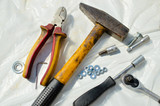 Hammer and other used repair tools on white plastic background
