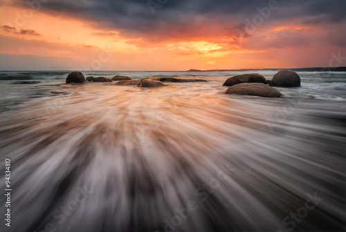 Fototapeta Naklejka Na Ścianę i Meble -  Sea sunrise. Stormy sea beach with slow shutter and waves flowing out