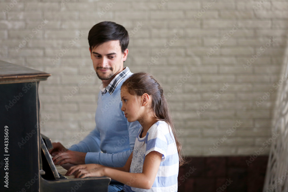 Musician teacher and little girl play piano together Musician teacher and little girl play piano together