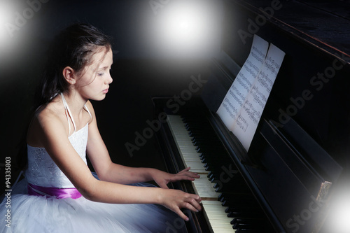 Beautiful girl playing on piano in classroom