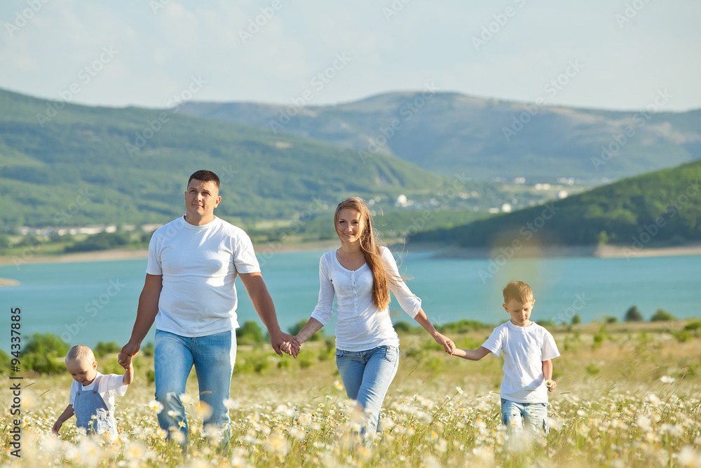 Happy family are walking in camomile field 