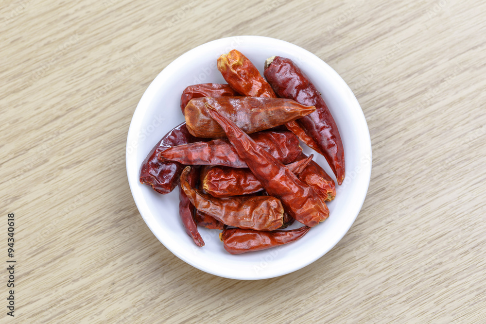 Dry red chili in white bowl on wooden table Dry red chili in white bowl on wooden table