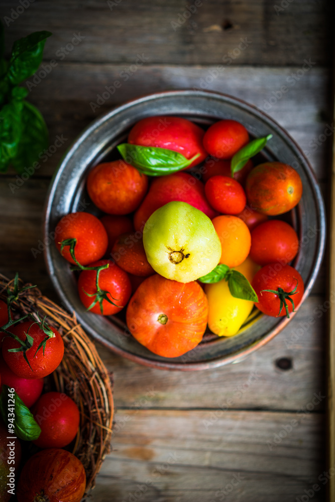 Multicolored tomatoes on rustic wooden background