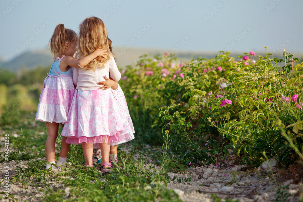 Three little girlfriends are playing in roses field Three little girlfriends are playing in roses field