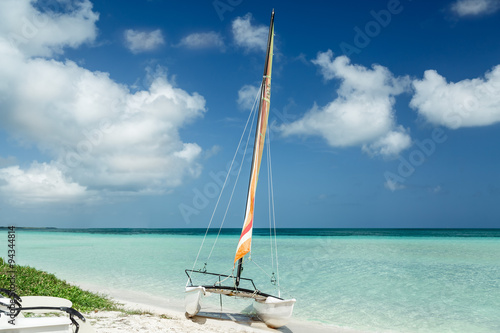 stunning beautiful, amazing view of sailboat resting on white sand Cuban beach on background of bright tranquil turquoise ocean water and deep blue sky