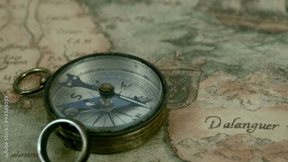 A small compass and a ring on top of a map. The map used for navigation shows the place Dalanguer A small compass and a ring on top of a map. The map used for navigation shows the place Dalanguer