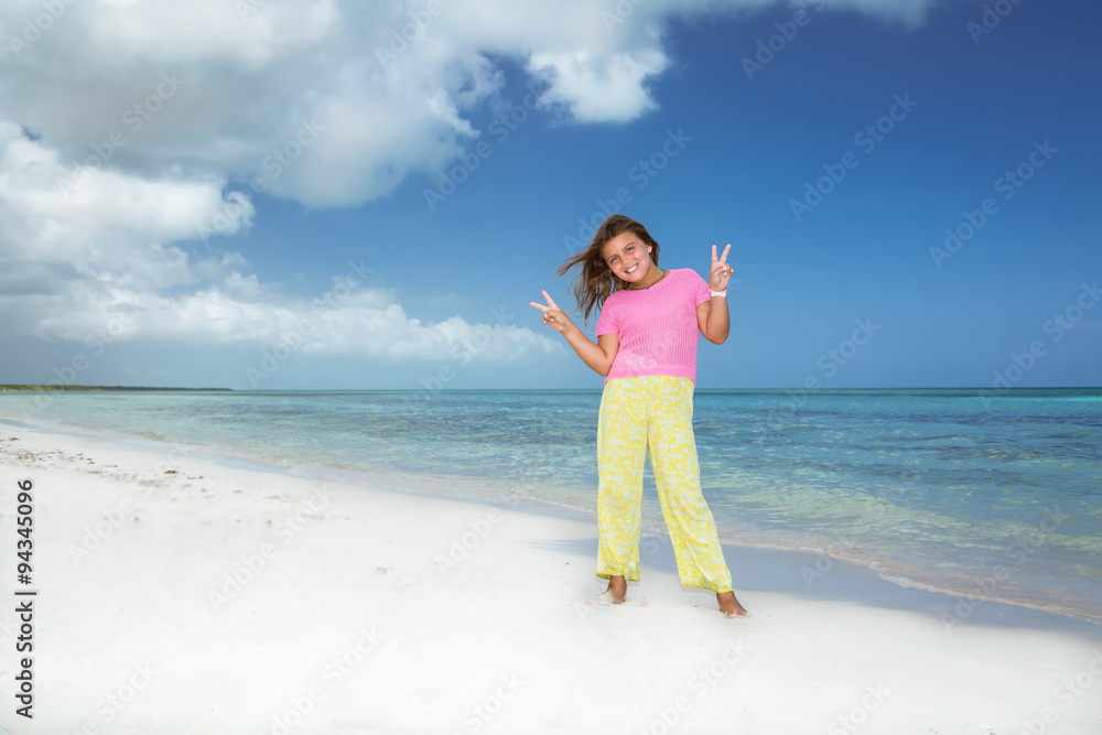 beautiful pretty fashionable little girl standing and holding her hands up on Cuban beach against turquoise ocean and blue sky background beautiful pretty fashionable little girl standing and holding her hands up on Cuban beach against turquoise ocean and blue sky background