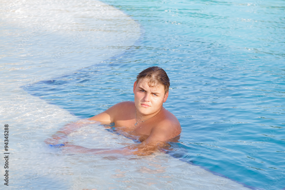 young adolescent handsome serious boy chilling out at swimming pool