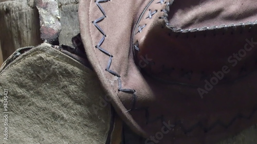 An old hat and a small bag hanged on the wood. These items are like things from a rodeo photo