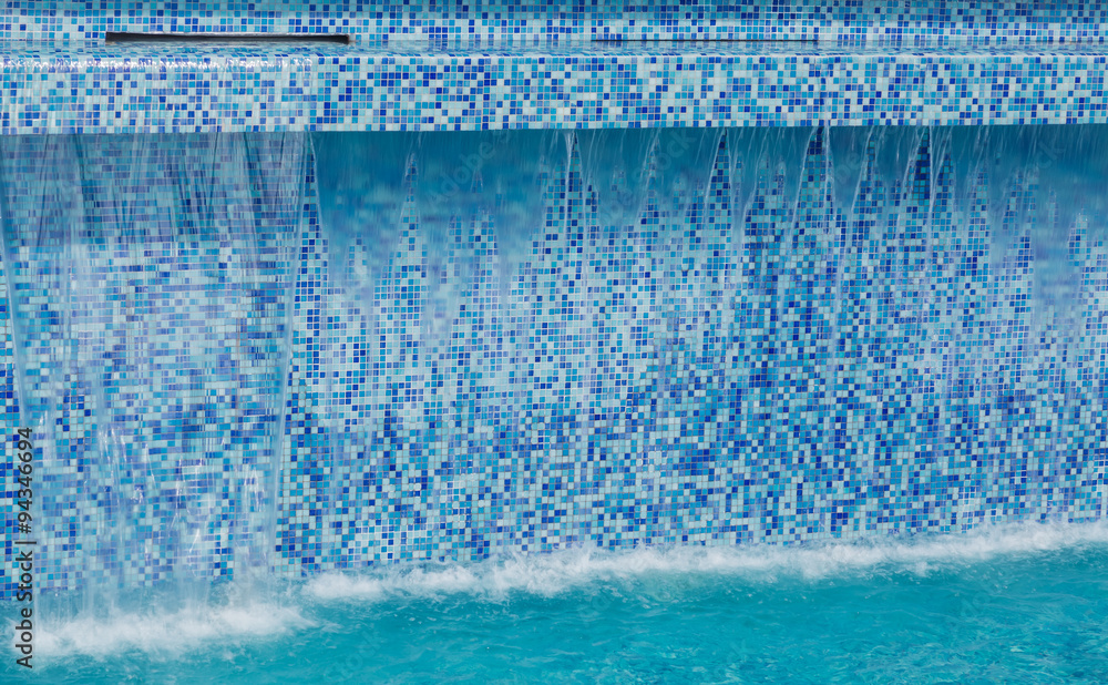 Fragment of view of amazing stylish gorgeous modern ceramic, mosaic tiles swimming pool tall wall with flowing water