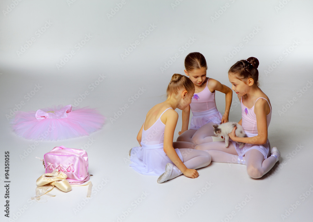 Fototapeta premium Three little ballet girls sitting in tutus and posing together