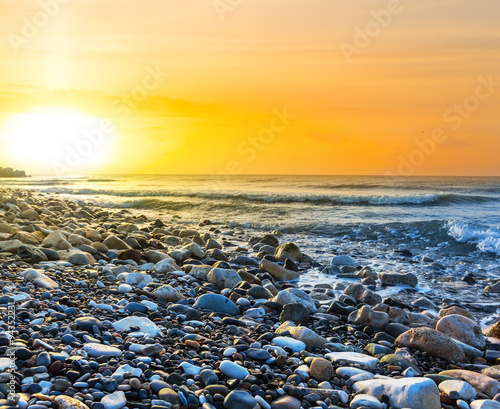 sunset over a stony sea coast © Yuriy Kulik