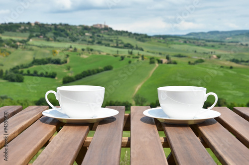 Two coffee cups on the wooden table against Tuscan landscape, It
