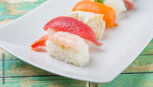 Various Japanese sushi type in white plate over wooden background