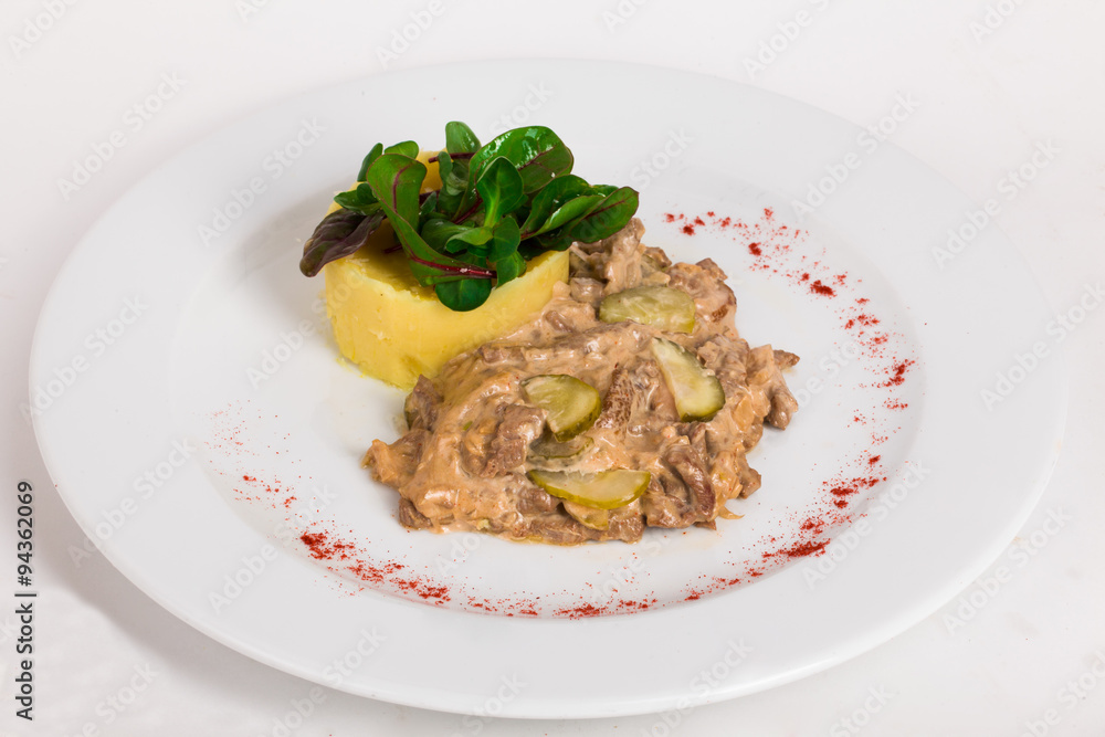 beef goulash stroganoff with pickles and mashed potatoes on a plate isolated white background close-up beef goulash stroganoff with pickles and mashed potatoes on a plate isolated white background close-up