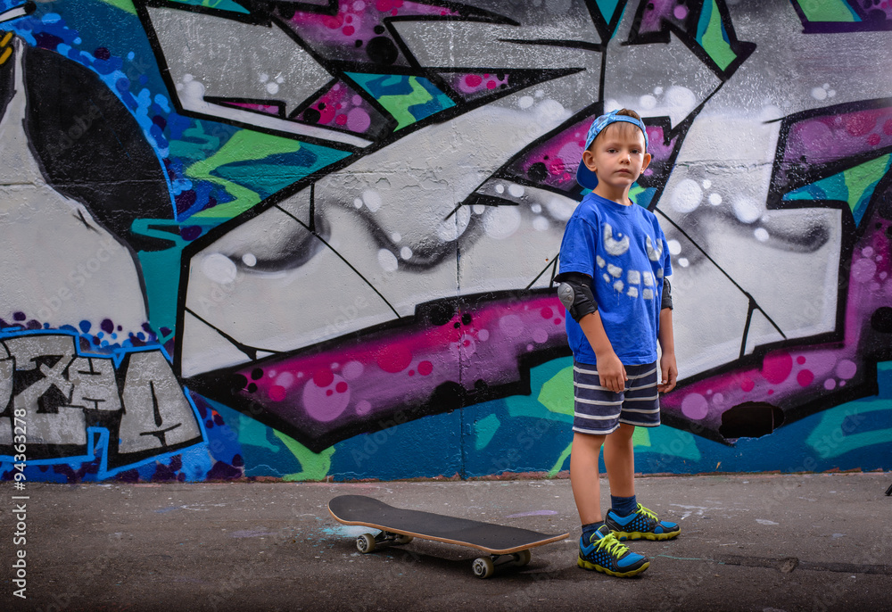 Fototapeta premium Little boy standing in front of vibrant graffiti
