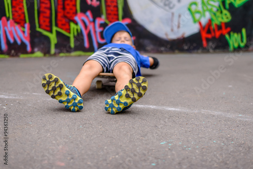 Young boy lying on his skateboard