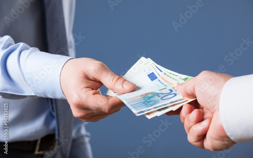 Businessman's  hands exchanging euro on blue background photo