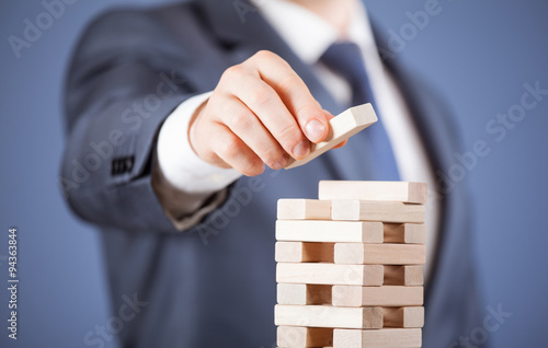 Unrecognizable businessman forming a wooden pyramid