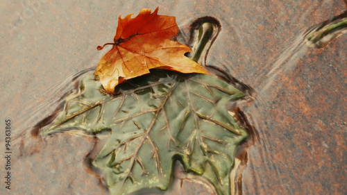 An autumnal vivid orange maple tree leaf sitting on top of a carved green counterpart to commemorate Canada's National Day
