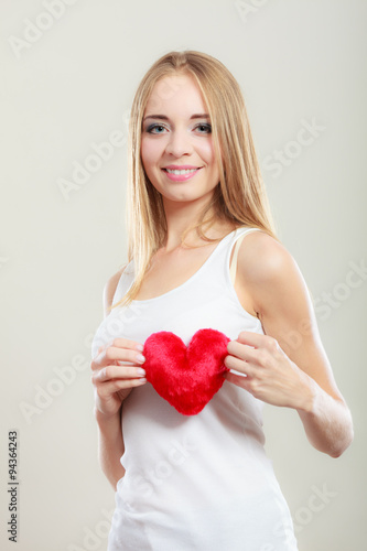 Smiling woman holding red heart love symbol