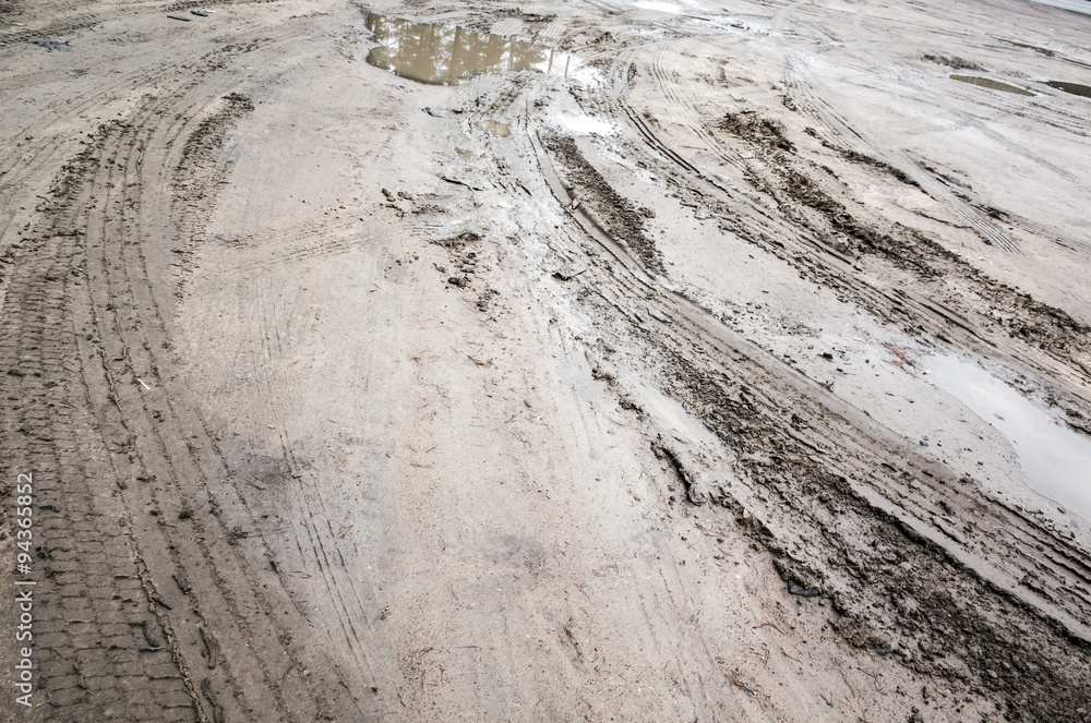 Fototapeta premium Tire tracks over mud dirty road with puddles