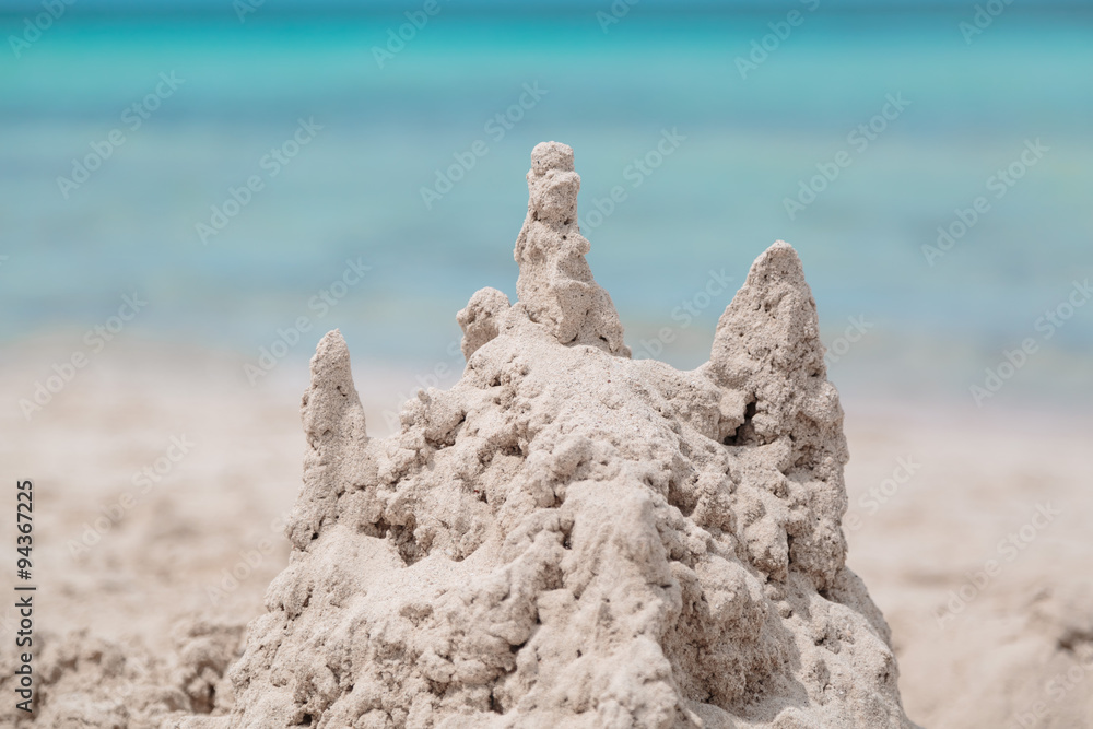 An interesting nicely built sand castle using a child's fantasy on the background of turquoise tranquil inviting ocean An interesting nicely built sand castle using a child's fantasy on the background of turquoise tranquil inviting ocean