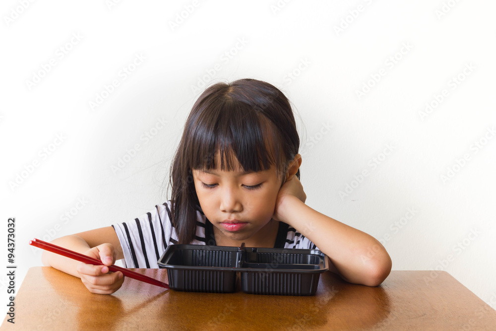 Bored children girl with red chopsticks sitting at the table Bored children girl with red chopsticks sitting at the table