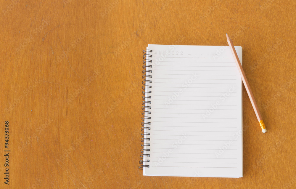 Blank notebook and pencils on the wooden table. View from above Blank notebook and pencils on the wooden table. View from above