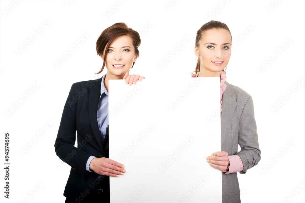 Two businesswomen carrying a big white board. Two businesswomen carrying a big white board.