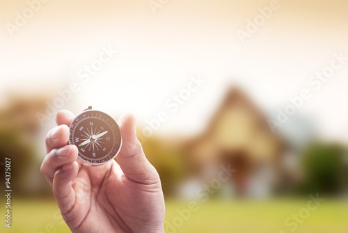 compass in hand on thai temple blur background with lighting fla