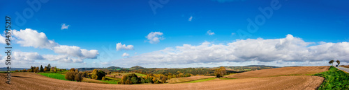 Panorama of foothill valley with plowed field in the spring