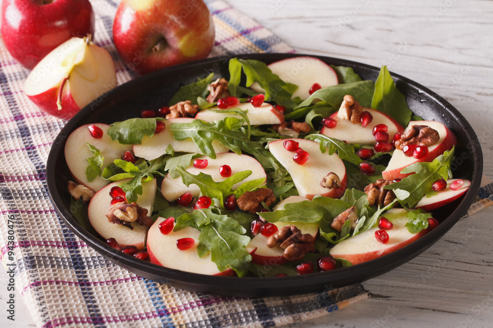 salad with red apples, pomegranate, walnuts and arugula close-up 
