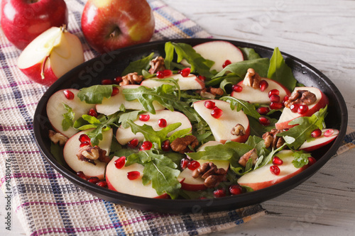 salad with red apples, pomegranate, walnuts and arugula close-up 
