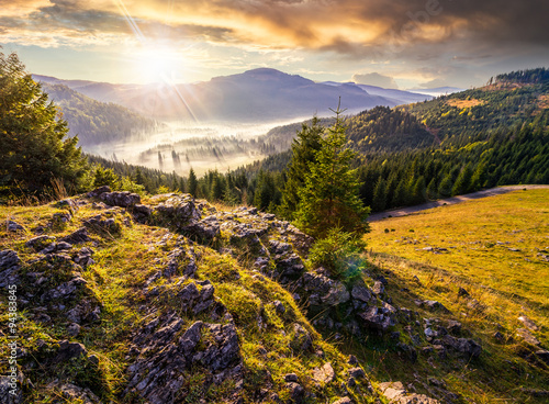 view from a rocky cliff to full of fog valley with conifer forest in high mountains of Apuseni Natural Park in Romania in evening light