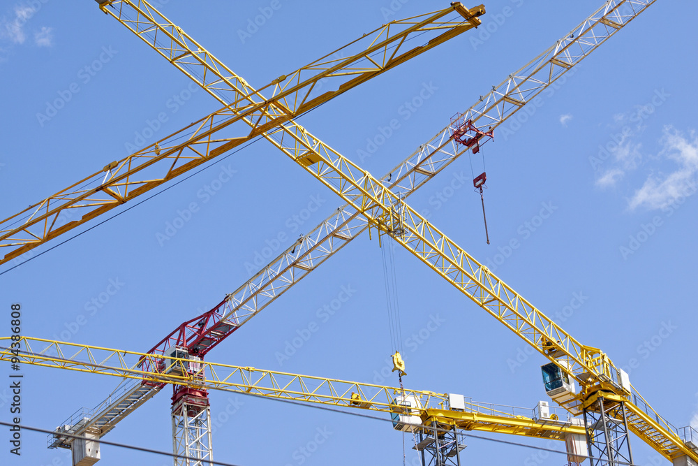 Industrial construction cranes over clear blue sky Industrial construction cranes over clear blue sky