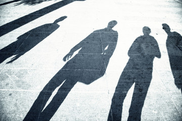 Grunge busy people shadows on paved city street on sunny day. People walk down the street.