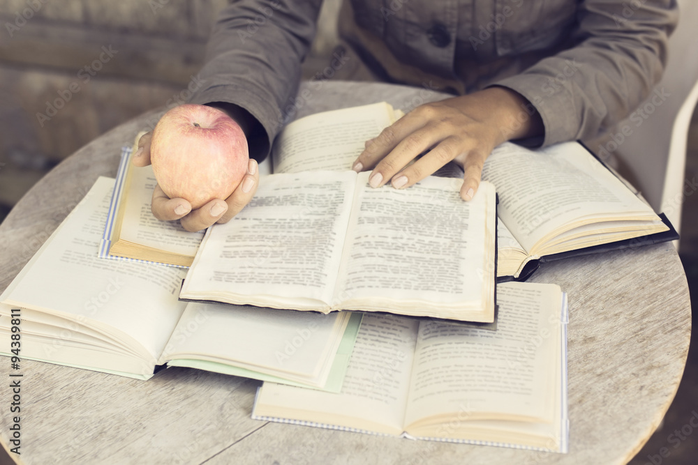 Girl reading a books outdoors with red apple Girl reading a books outdoors with red apple