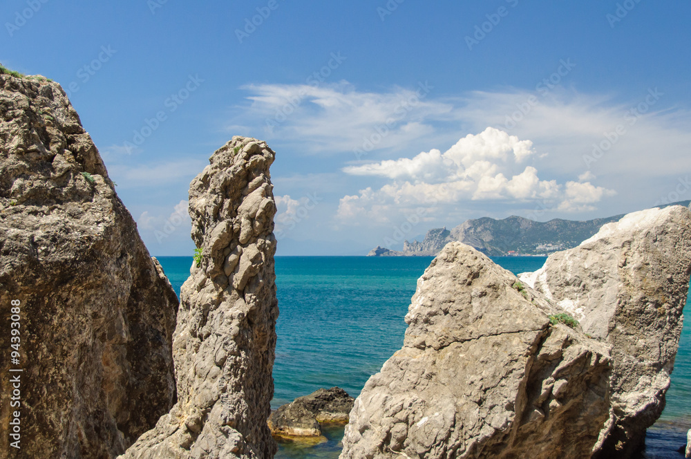 Broken rocks on the bank of the blue sea with blue sky and clouds