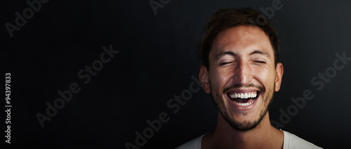 Portrait of cute young man wearing white tshirt and laughing a lot. Wide