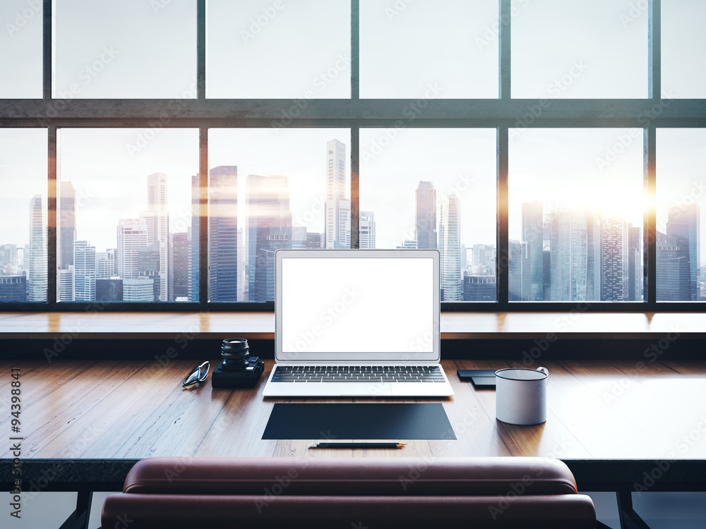 Photo of laptop on the worksplace with panoramic windows. City at sunrise in a background. 3D rendering Photo of laptop on the worksplace with panoramic windows. City at sunrise in a background. 3D rendering