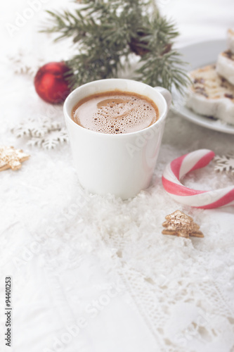 A cup of coffee with cake and candy cane on christmas background. Toned