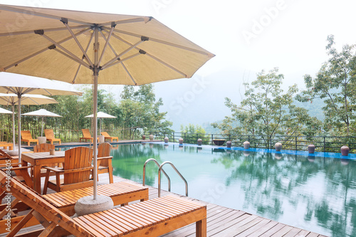 Umbrella chair in hotel pool resort with sunset