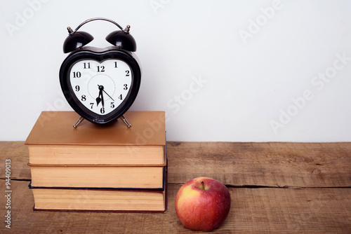 books, alarm clock and apple on wooden background. Education equipment, education concept