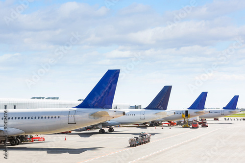 Tails of some airplanes at airport during boarding operation photo