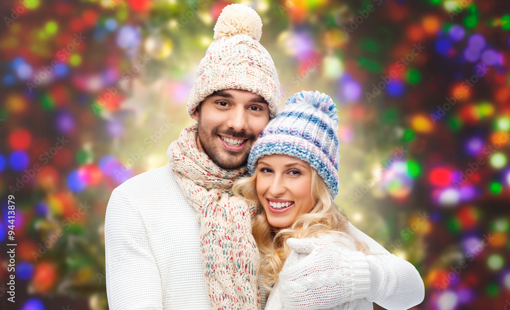 Obraz premium happy couple in winter clothes hugging over lights