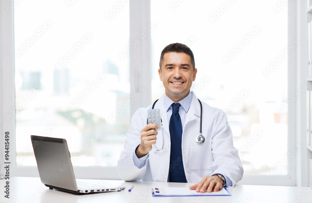smiling doctor with tablets and laptop in office